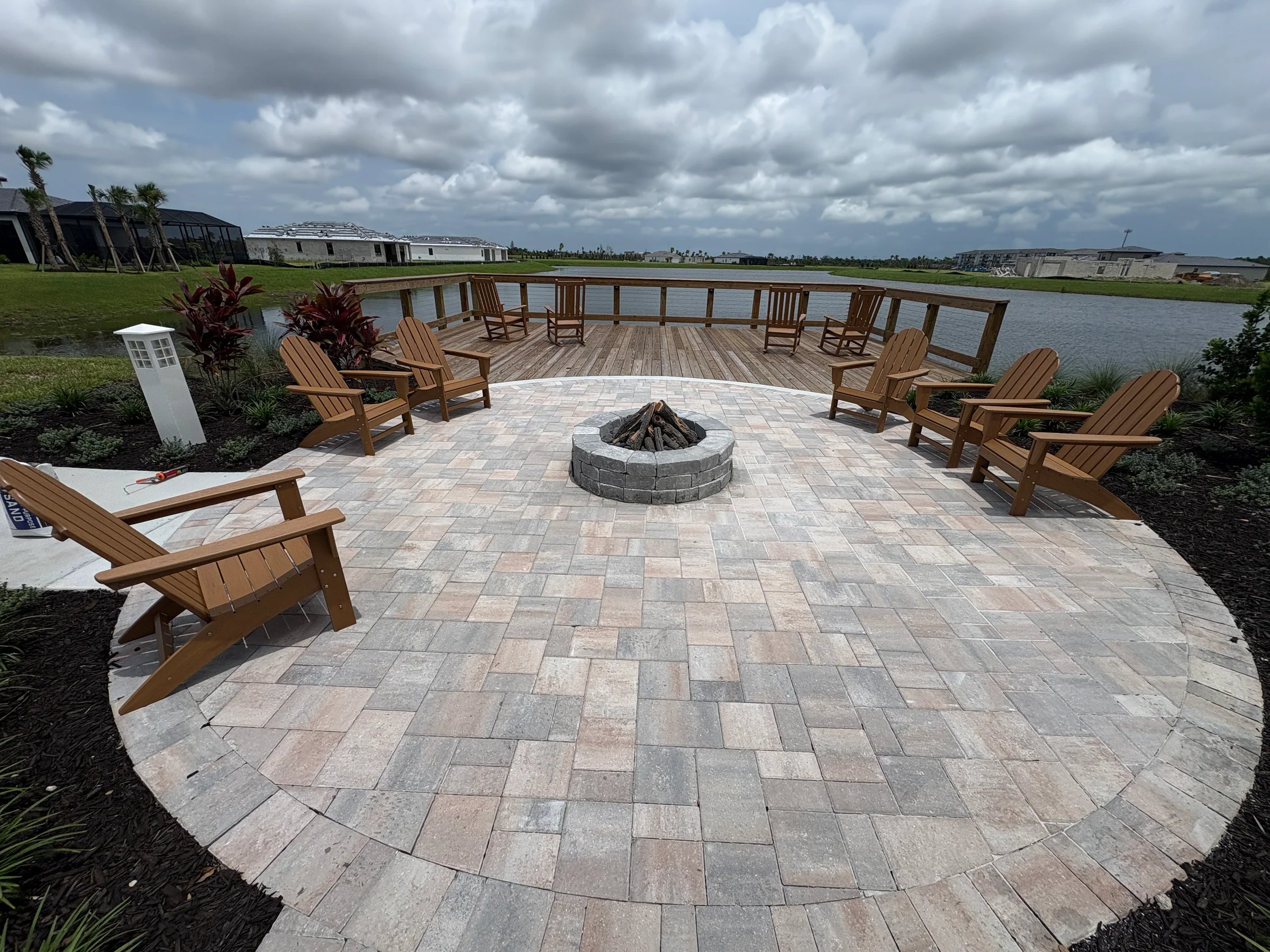 Completed circular paver patio and fire pit beside a pond